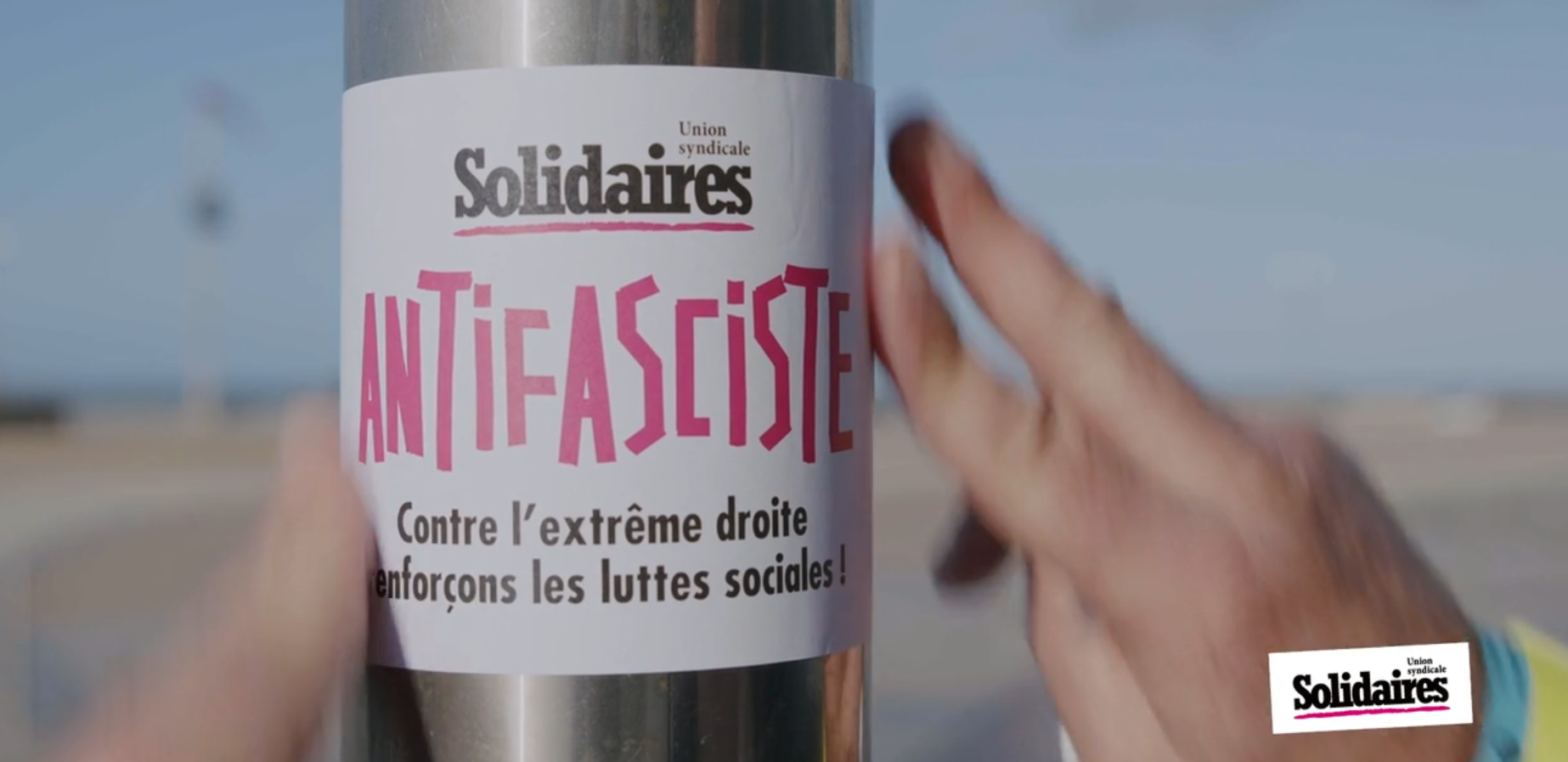 collage d'autocollant antifa solidaires sur un poteau